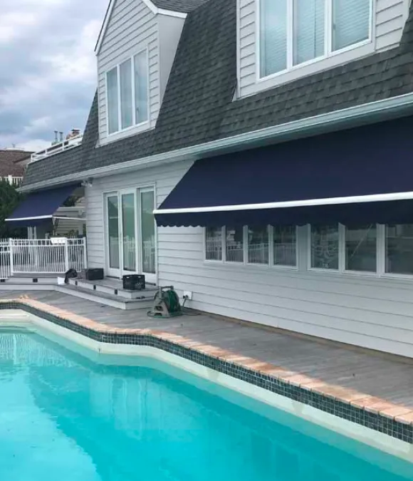 Dark blue rectractable awning installed on windows beside a pool in Eatontown, NJ